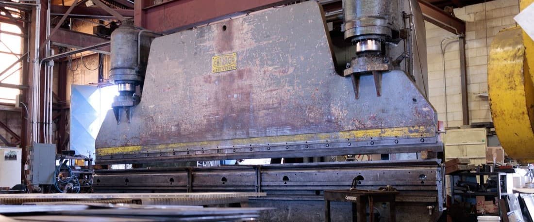 Prensa pesada instalada sobre pies de máquina en una nave de producción